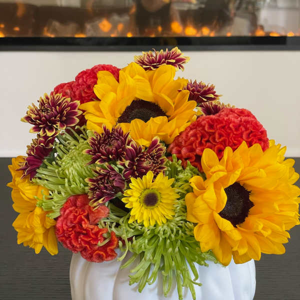 Sunflowers and mixed chrysanthemums arranged in a white pumpkin vase