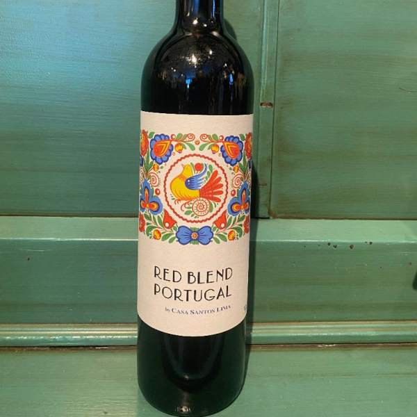 Bottle of red wine with a colorful label on a green wooden surface