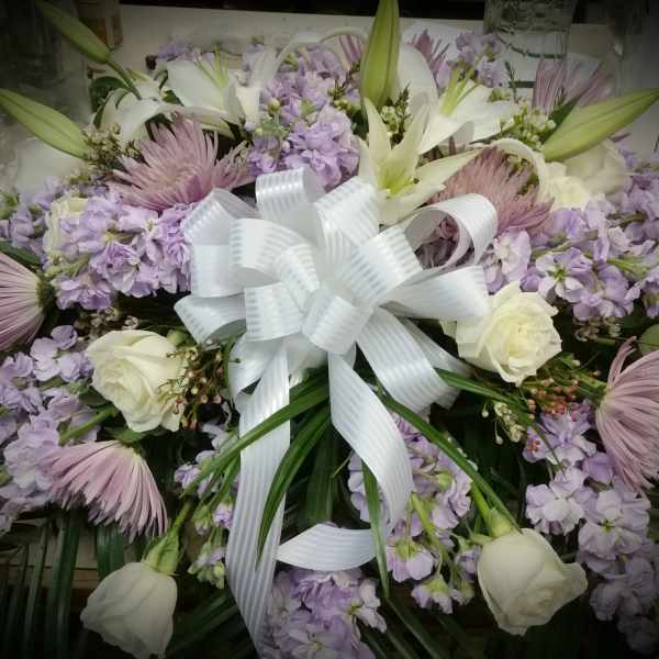 Lavender and white floral arrangement with a large white ribbon bow