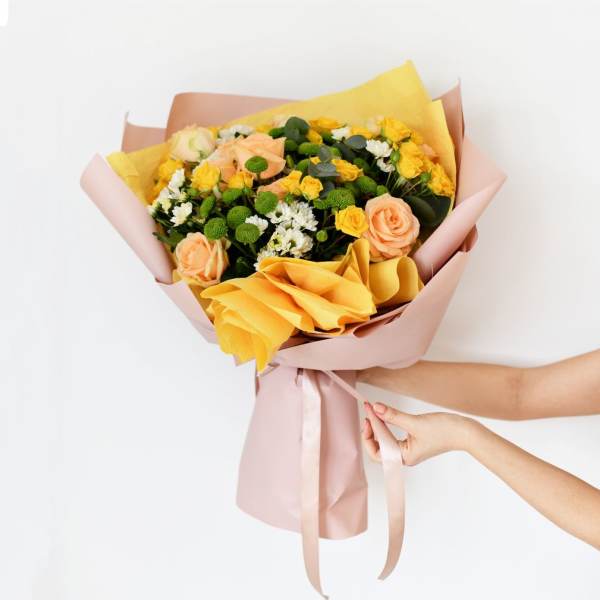 Bouquet of yellow and peach roses wrapped in pink paper