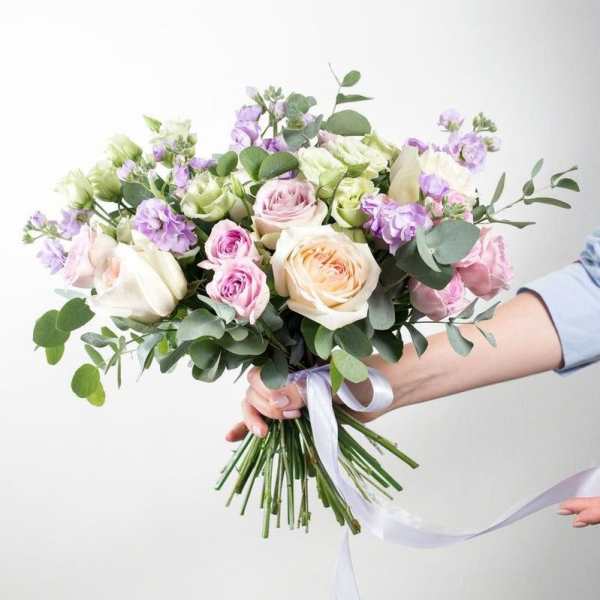 Hand-tied bouquet of pastel roses and purple flowers with ribbon