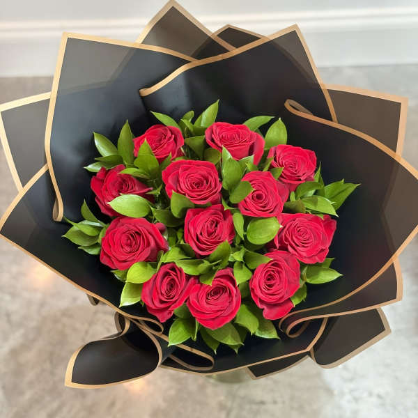 Bouquet of hot pink roses wrapped in black paper with gold trim