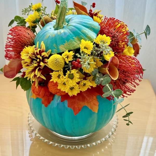 Bright autumn bouquet arranged around a painted blue pumpkin centerpiece
