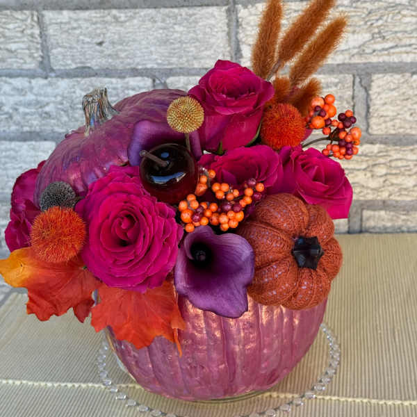 Pink roses and purple calla lilies arranged in a painted pumpkin vase
