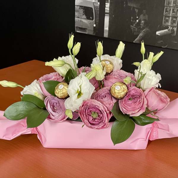 Pink and white flower bouquet with gold-wrapped chocolates on pink paper