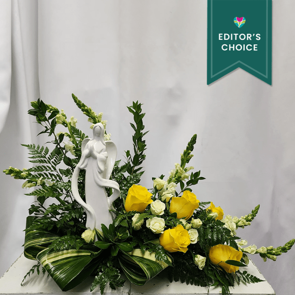 Yellow roses and white flowers arranged around a white angel statue