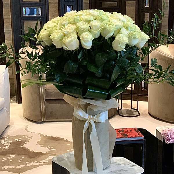 Large bouquet of white roses in a wrapped vase with a ribbon