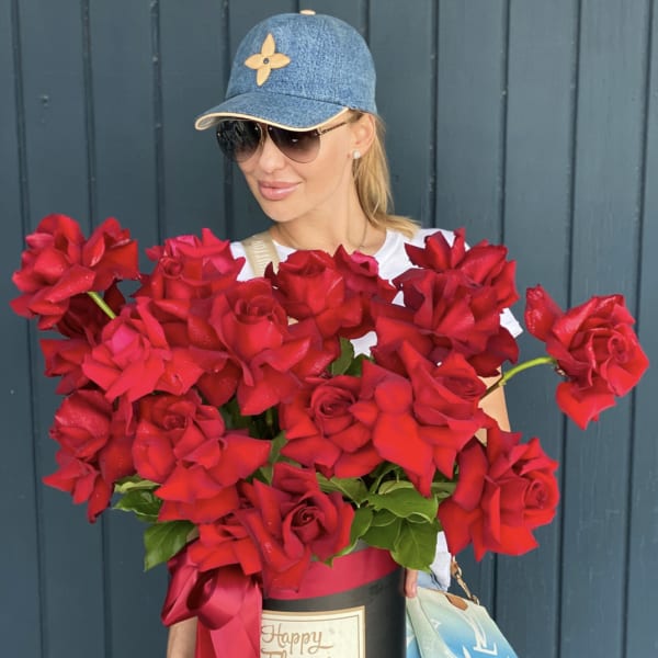 Woman holding a large box of red roses with a ribbon