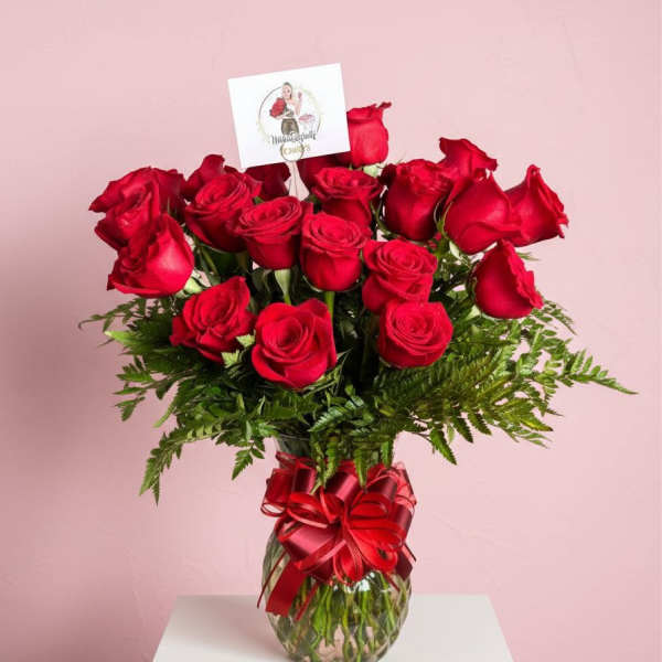 Red roses in a glass vase with a red ribbon bow