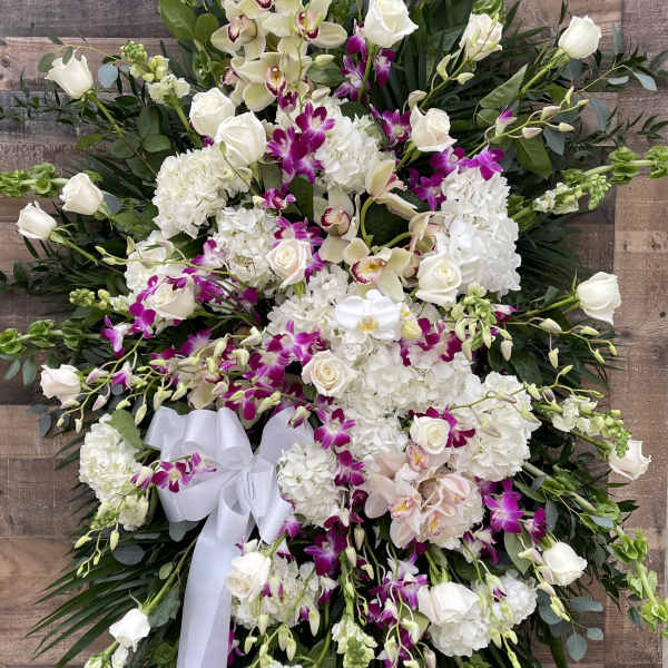 Large white and purple floral standing spray on an easel with a ribbon