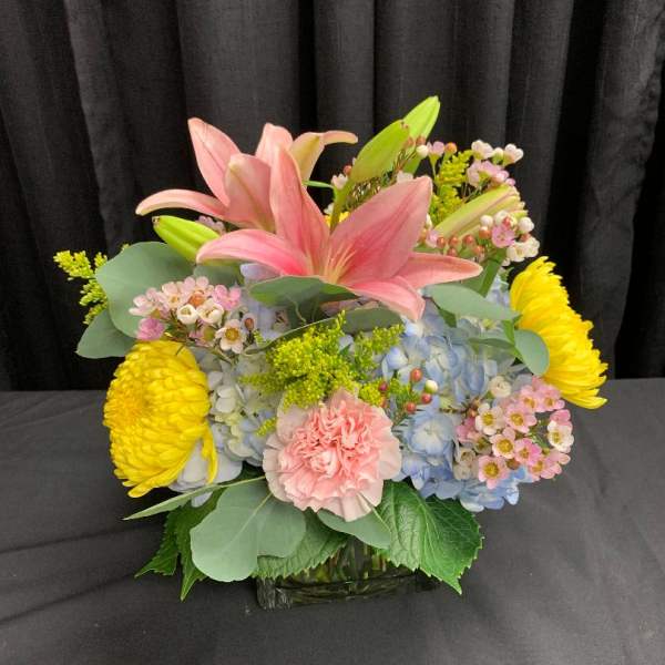 Pink lilies and mixed blooms in a glass vase