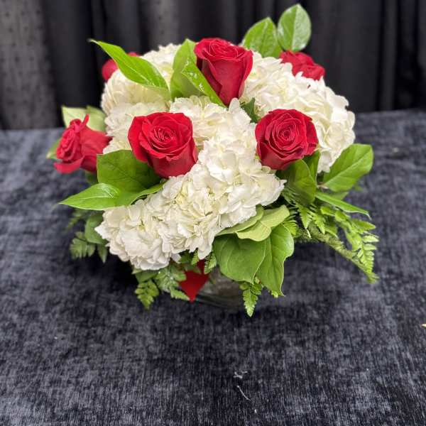 Red roses and white hydrangeas arranged in a low vase