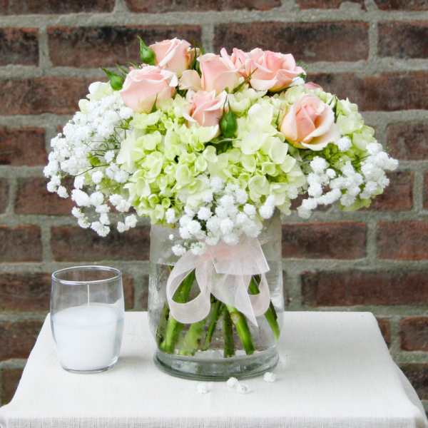 Pink roses and white hydrangeas in a glass vase with a ribbon