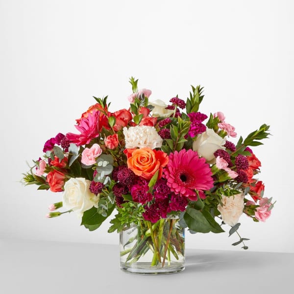 Mixed bouquet of roses, gerbera daisies, and carnations in a glass vase