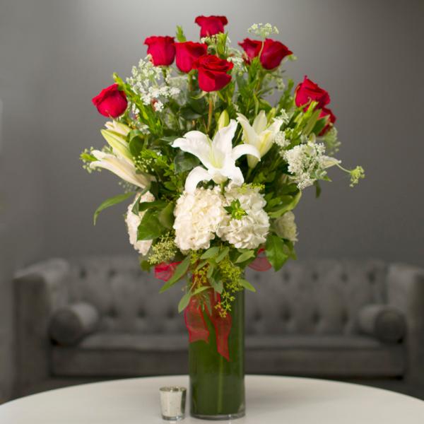 Red roses and white lilies in a tall glass vase