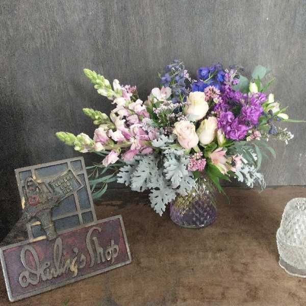 Mixed bouquet of purple, pink, and white flowers in a glass vase
