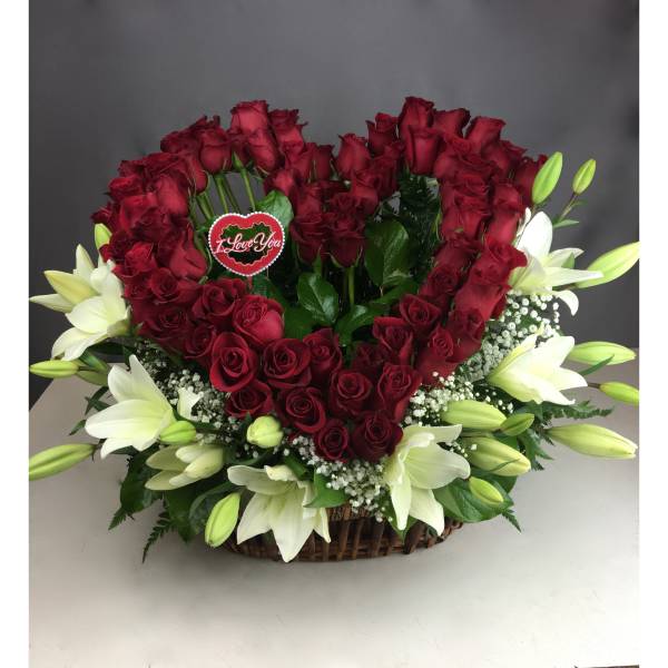Heart-shaped rose arrangement with white lilies in a basket