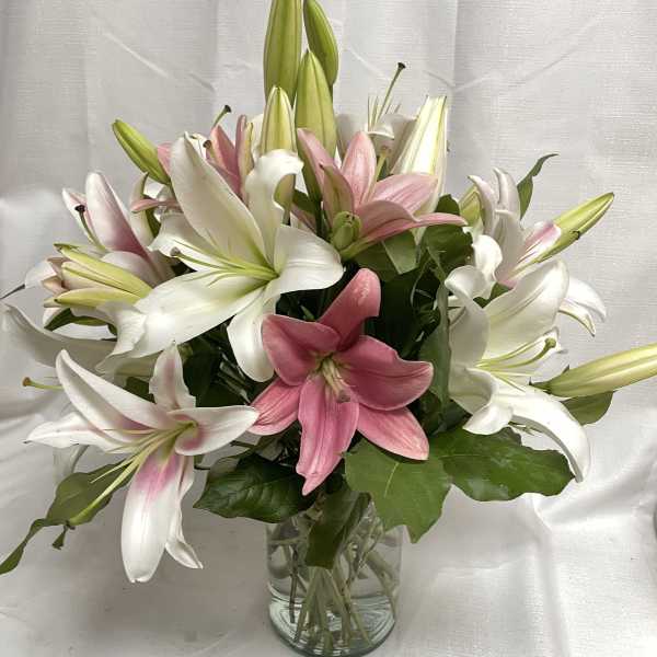 Pink and white lilies arranged in a clear glass vase