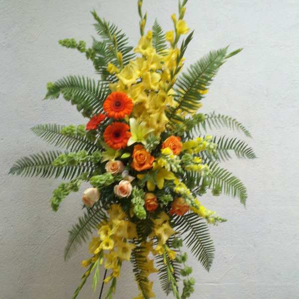 Tall floral spray with yellow and orange flowers on a stand