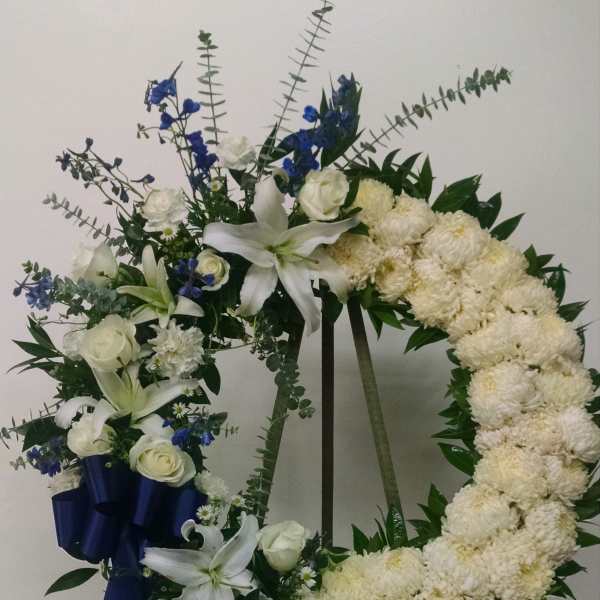 White floral wreath on an easel with blue ribbon accents