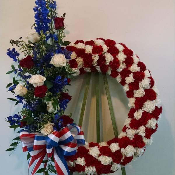 Floral wreath on an easel with red and white carnations and blue roses
