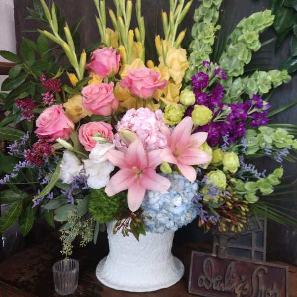 Mixed floral arrangement in a white vase with pink roses and lilies