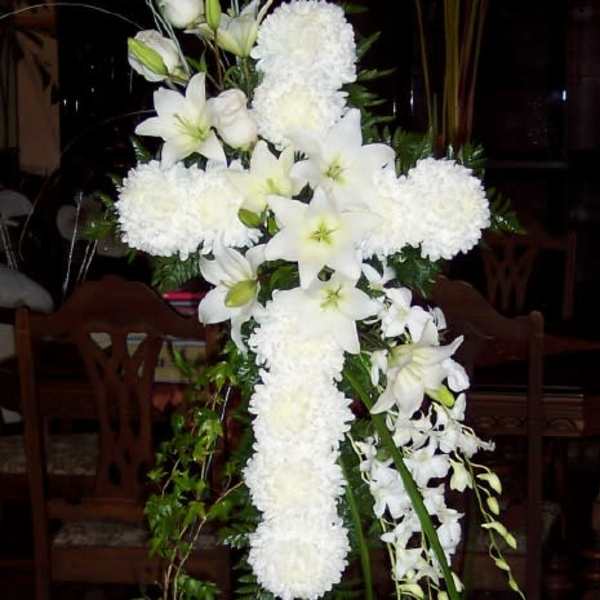 White floral cross arrangement with lilies and pompons on a stand