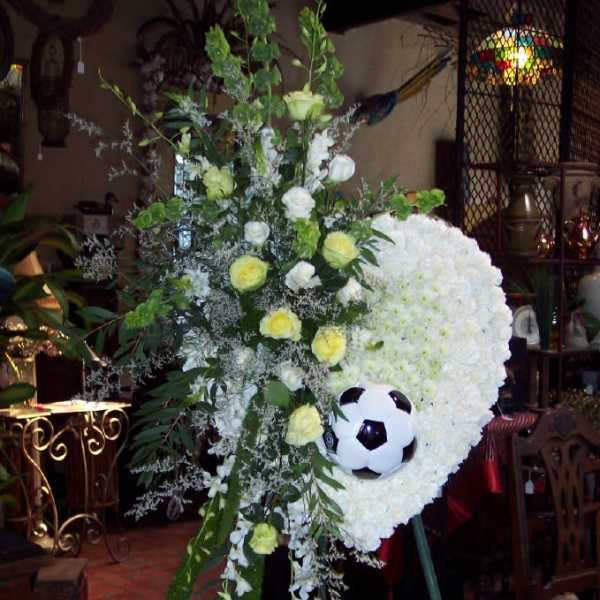 Standing floral tribute with white blooms and a soccer ball centerpiece