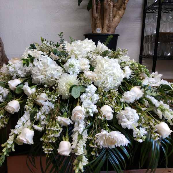 Large white funeral spray with roses, hydrangeas, and chrysanthemums