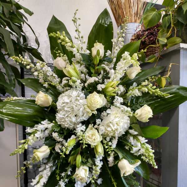 Large white floral standing spray with lilies, roses, and hydrangeas