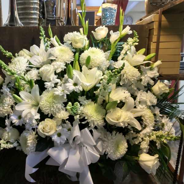 Large white floral arrangement with roses, lilies, and chrysanthemums