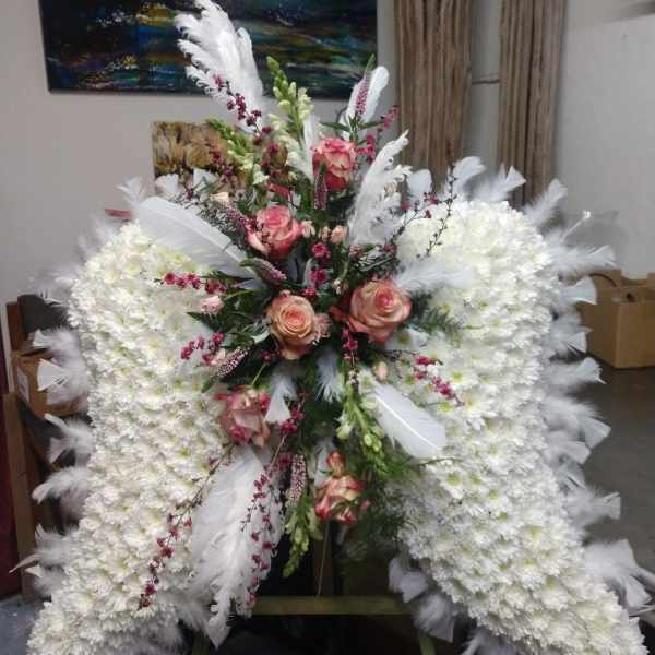 Large white floral standing spray with pink roses and white feathers