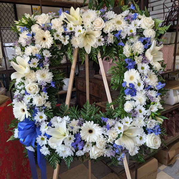 Large white and blue floral wreath on a wooden easel