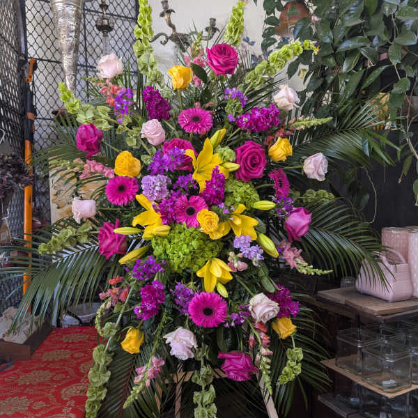 Large standing floral spray with pink, yellow, and green blooms