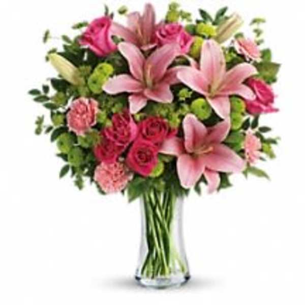 Pink lilies and roses arranged in a clear glass vase