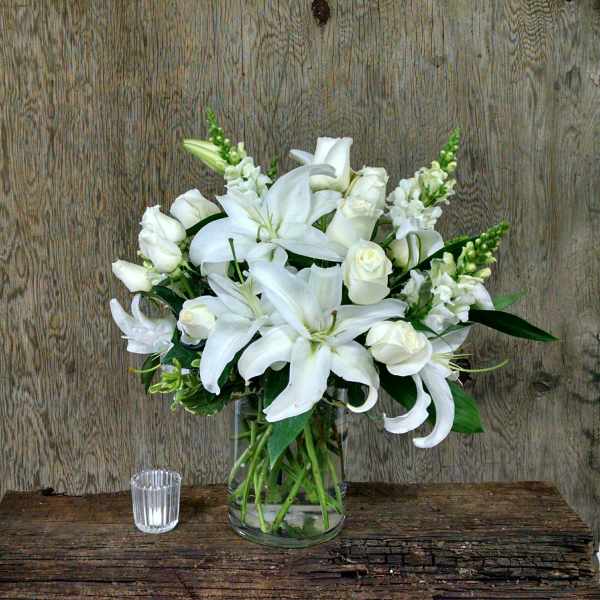 White lilies and roses arranged in a clear glass vase