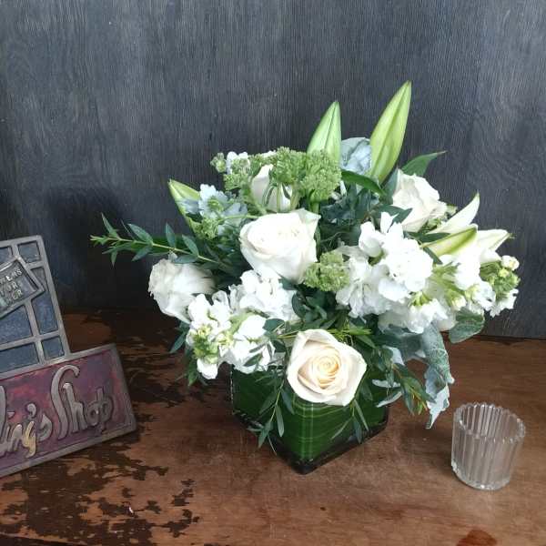 White roses and lilies arranged in a green vase.