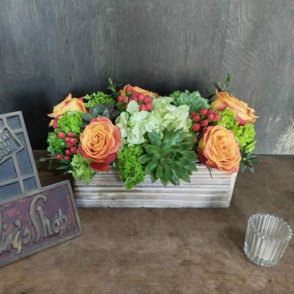 Rectangular floral arrangement with orange roses and succulents in a wooden box