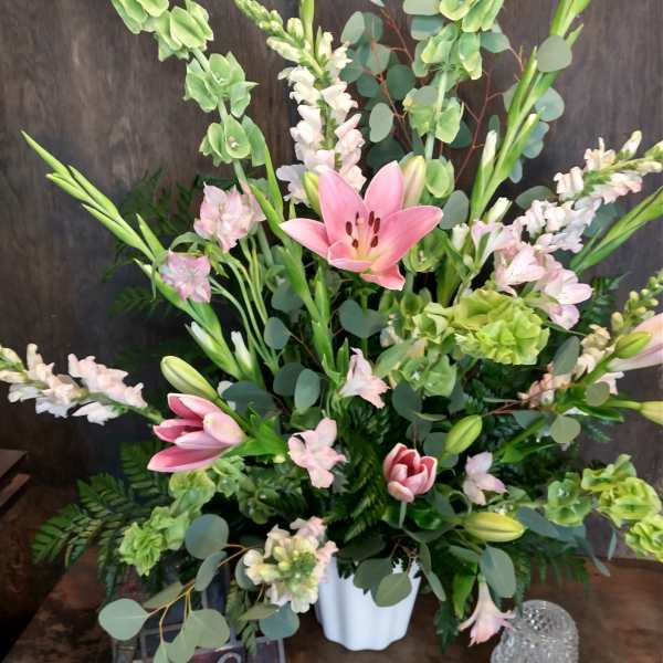 Pink lilies and pale blooms arranged in a white vase