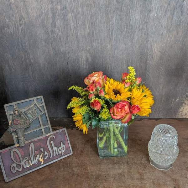 Bouquet of sunflowers and pink roses in a square glass vase