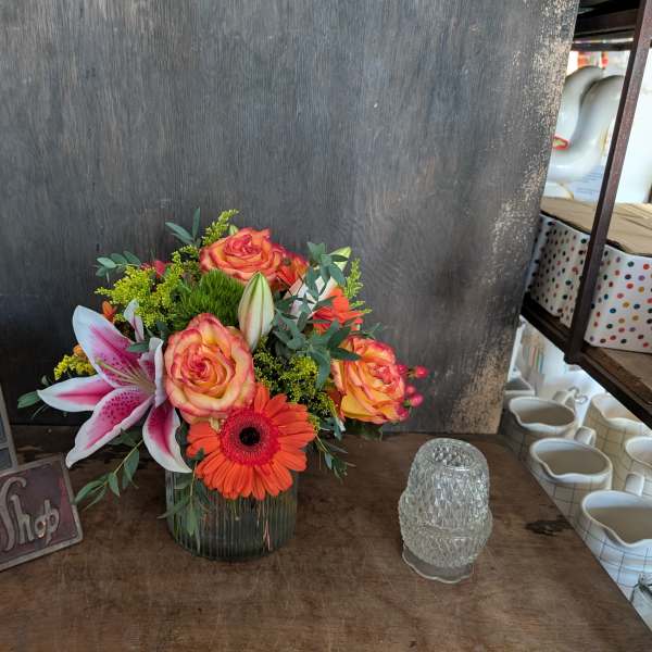 Mixed bouquet in a glass vase with roses, lilies, and orange gerbera daisies