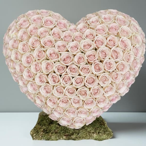 Heart-shaped arrangement of pale pink roses on a moss base