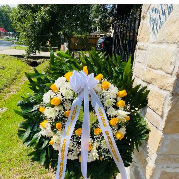 Standing funeral wreath of yellow roses and white flowers with a ribbon