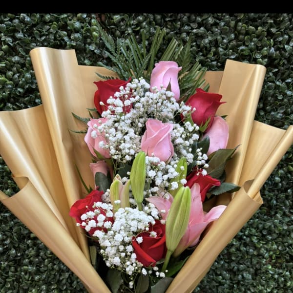 Bouquet of pink and red roses with white baby's breath in gold wrap