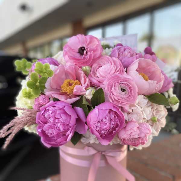 Pink bouquet in a round pink box tied with ribbon