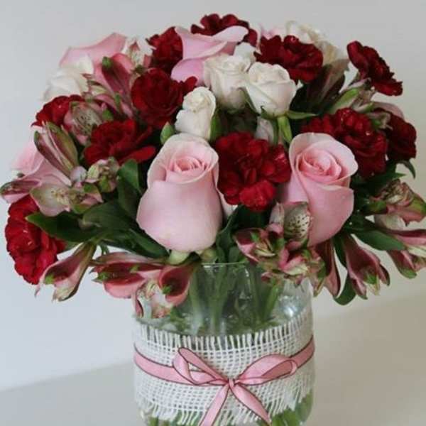 Pink and red flower bouquet in a glass vase with a pink ribbon