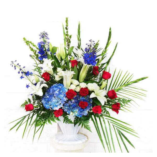 Large arrangement of red roses, white lilies, and blue hydrangeas in a white vase