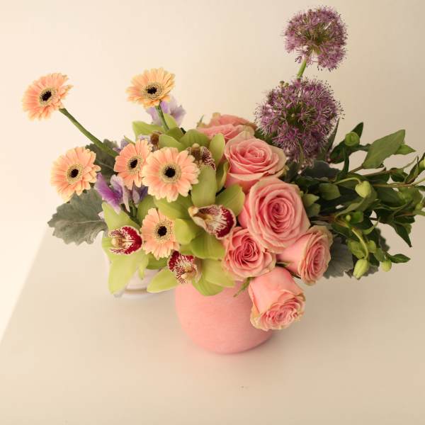 Pink roses and peach gerbera daisies in a pink vase