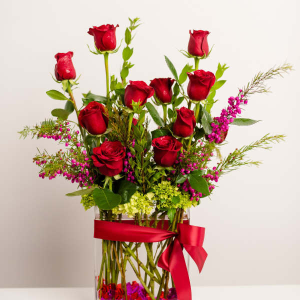 Red roses in a clear square vase with a red ribbon