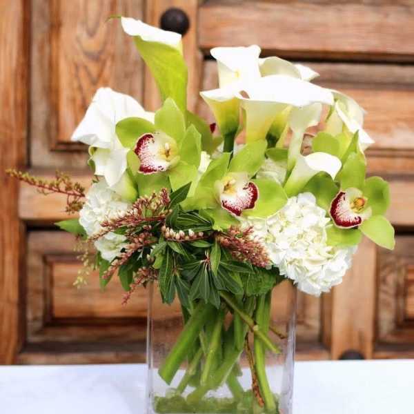 White calla lilies and orchids in a clear glass vase